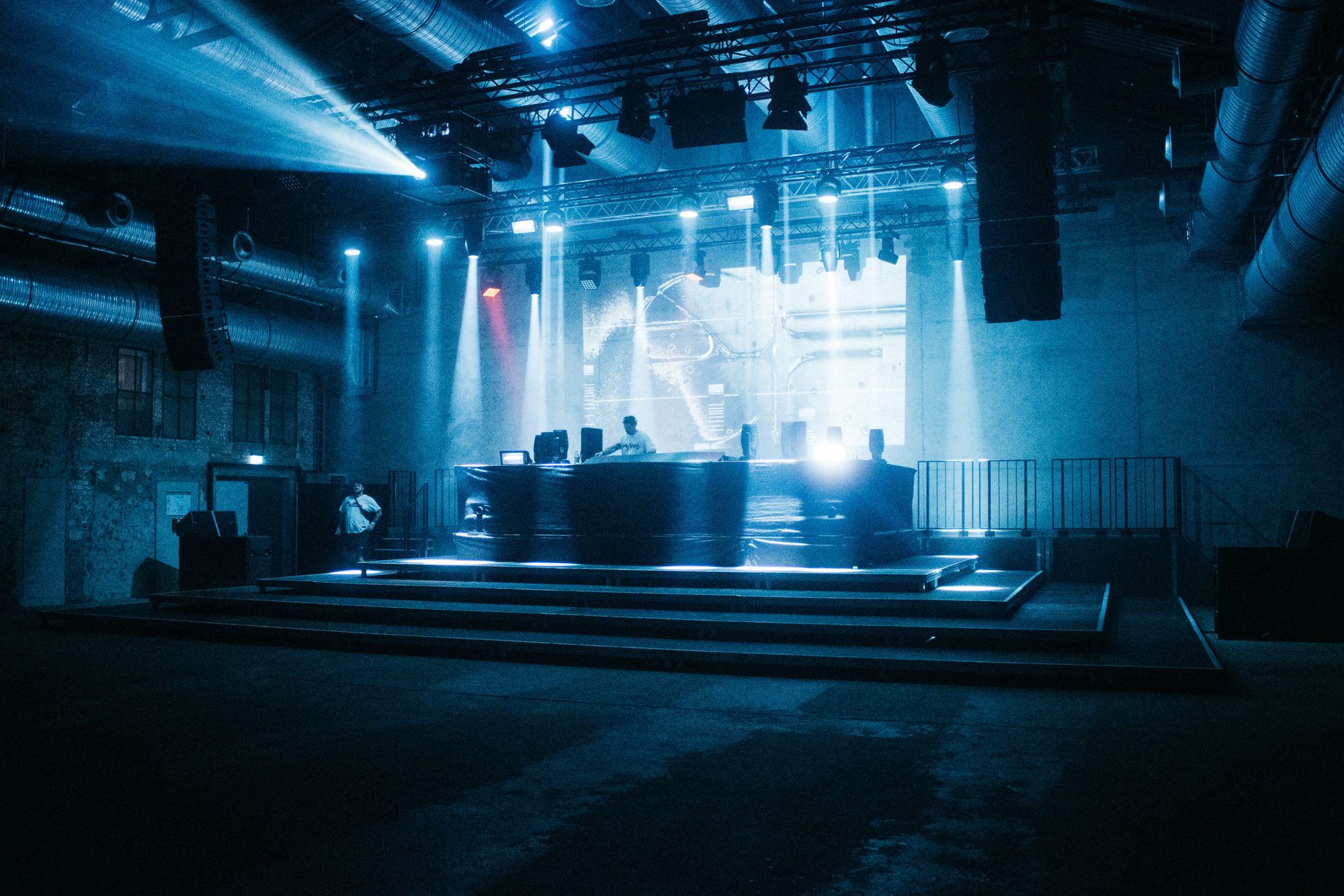 Bühne in den Wagenhallen in blauem Licht mit DJ-Pult und Lichtkegeln