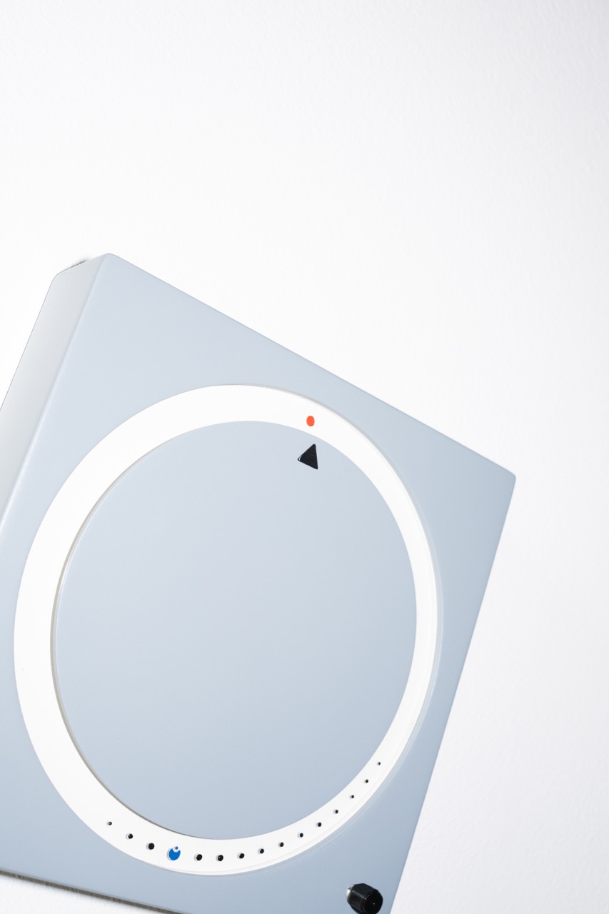 Detail der Uhr schräg von oben mit rotem Punkt und Zeiger